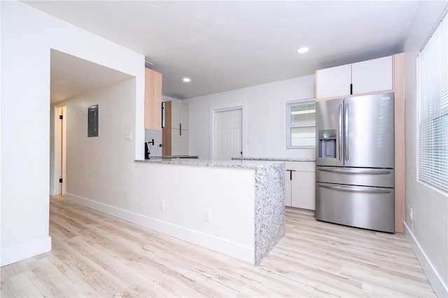 2002 Geigel Ave, Orlando, FL 32806 - kitchen featuring stainless steel refrigerator with ice dispenser, electric panel, light wood-style floors, white cabinetry, and baseboards
