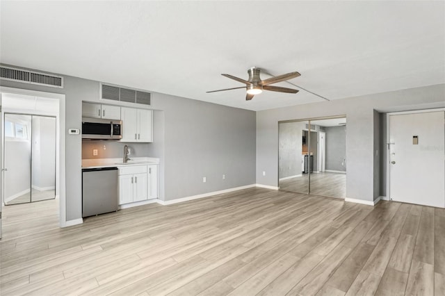 unfurnished living room featuring light wood-type flooring, sink, and ceiling fan