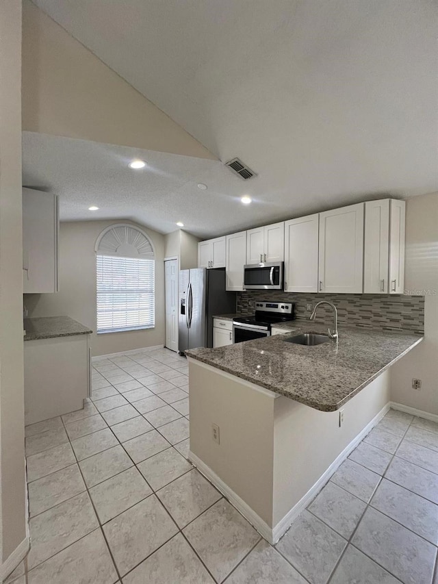 kitchen featuring appliances with stainless steel finishes, sink, white cabinets, light tile patterned floors, and kitchen peninsula