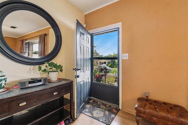 foyer entrance with crown molding, light wood-type flooring, and a wealth of natural light