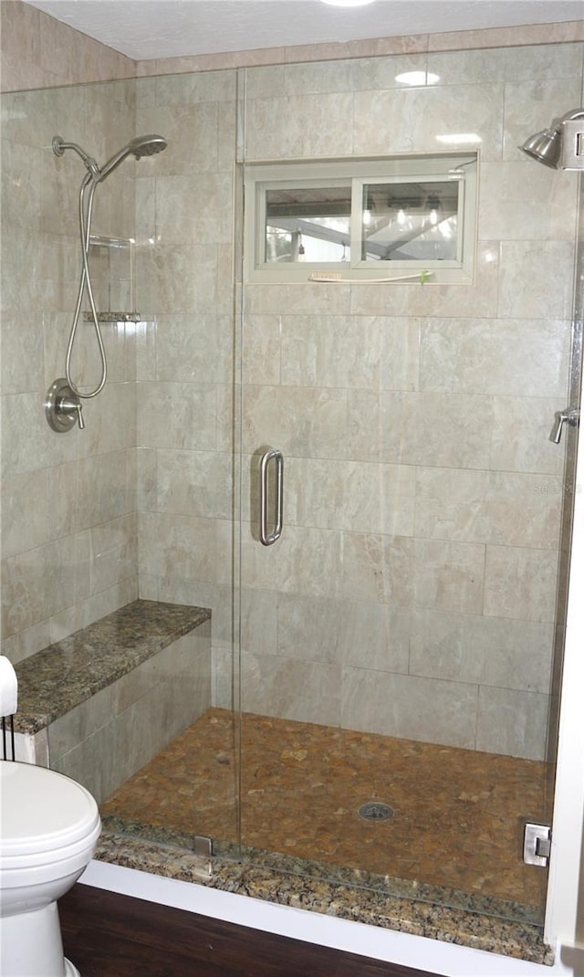 bathroom featuring toilet and a shower with door