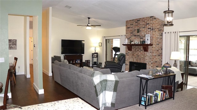 living room featuring ceiling fan, a brick fireplace, and dark hardwood / wood-style flooring