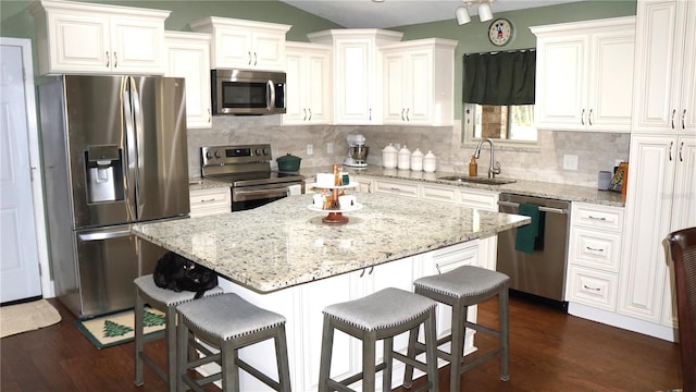 kitchen featuring white cabinetry, stainless steel appliances, sink, a kitchen breakfast bar, and a center island