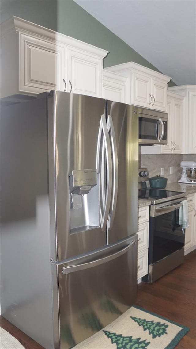 kitchen featuring white cabinetry, stainless steel appliances, tasteful backsplash, dark hardwood / wood-style floors, and vaulted ceiling