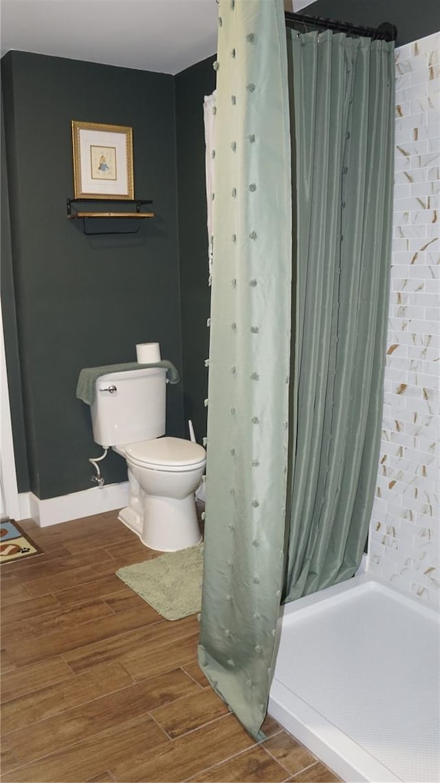 bathroom with toilet, wood-type flooring, and walk in shower