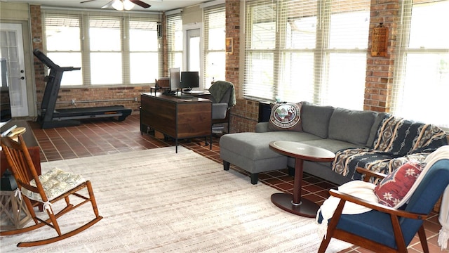 tiled living room with ceiling fan, a wealth of natural light, and brick wall