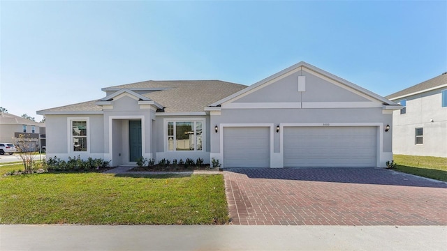 view of front of house with a garage, decorative driveway, a front yard, and stucco siding