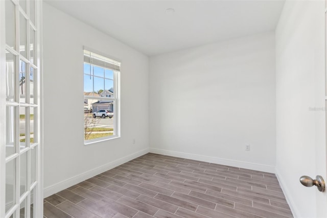 spare room with baseboards and wood finished floors