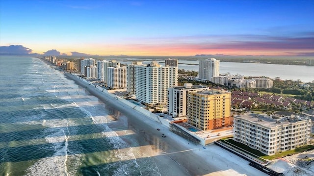 aerial view at dusk with a water view and a view of the beach