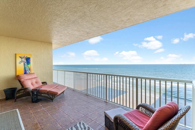 balcony featuring a view of the beach and a water view