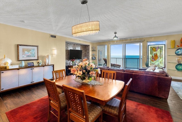 dining room featuring crown molding, dark hardwood / wood-style floors, ceiling fan, and a textured ceiling