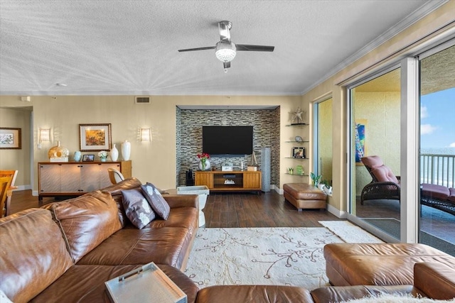 living room with ceiling fan, crown molding, dark wood-type flooring, and a textured ceiling