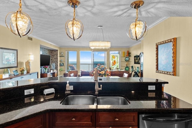 kitchen featuring sink, crown molding, dark stone countertops, decorative light fixtures, and stainless steel dishwasher