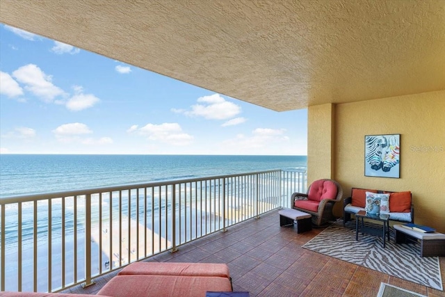 balcony with a water view, a beach view, and an outdoor hangout area