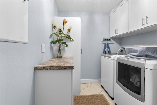 washroom with cabinets, washer and clothes dryer, and light tile patterned floors