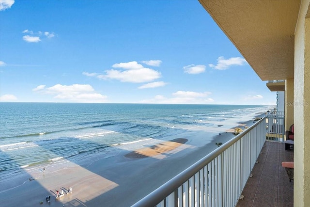 balcony with a water view and a view of the beach