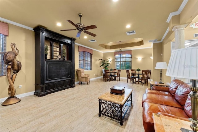 living room featuring ceiling fan, ornamental molding, a tray ceiling, and light hardwood / wood-style flooring