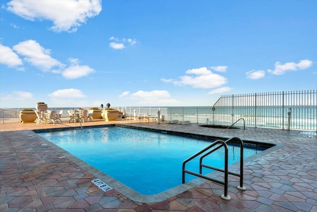 view of pool with a water view and a patio