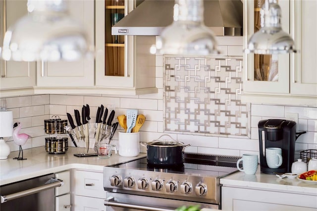 kitchen with backsplash, range hood, white cabinets, and appliances with stainless steel finishes