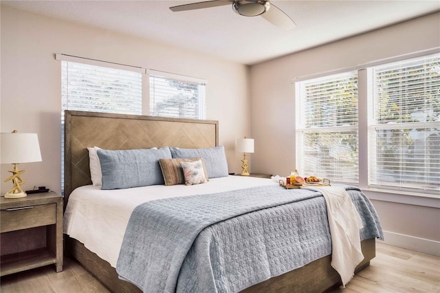 bedroom featuring multiple windows, light hardwood / wood-style floors, and ceiling fan