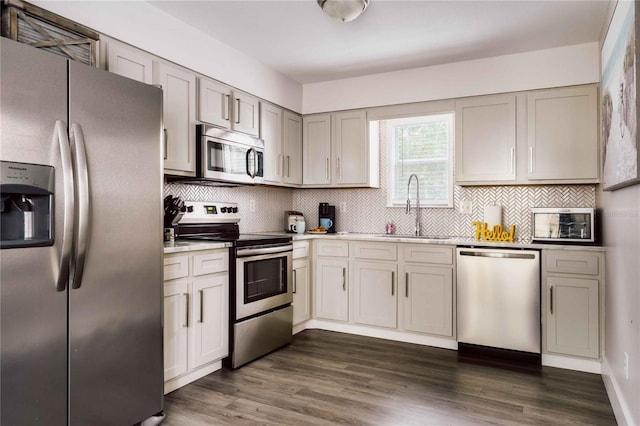 kitchen featuring sink, gray cabinets, stainless steel appliances, dark hardwood / wood-style floors, and tasteful backsplash