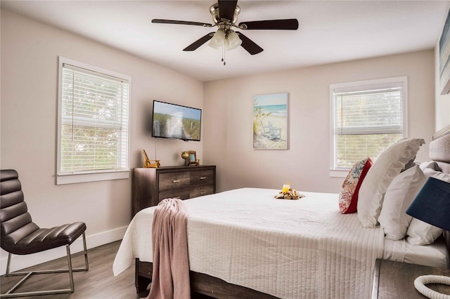 bedroom with multiple windows, ceiling fan, and light hardwood / wood-style floors