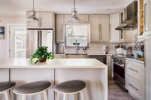 kitchen featuring sink, a kitchen breakfast bar, decorative backsplash, high end appliances, and wall chimney range hood