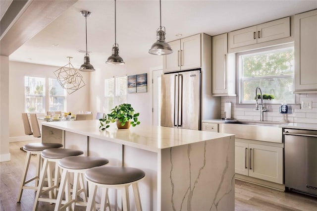 kitchen with stainless steel appliances, a center island, a kitchen breakfast bar, decorative backsplash, and decorative light fixtures