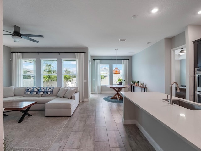 living room featuring ceiling fan, sink, and a textured ceiling