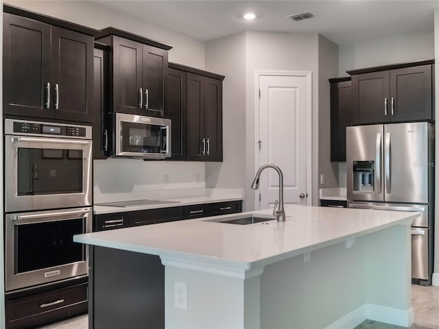 kitchen featuring sink, appliances with stainless steel finishes, and a center island with sink