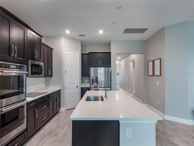 kitchen featuring sink, dark brown cabinetry, stainless steel appliances, and a kitchen island with sink