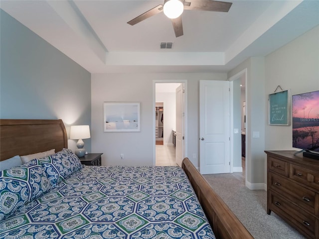 carpeted bedroom featuring ceiling fan and a raised ceiling