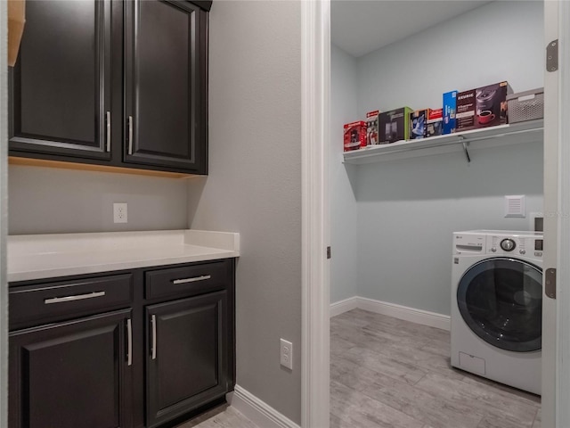 clothes washing area with cabinets, washer / dryer, and light wood-type flooring