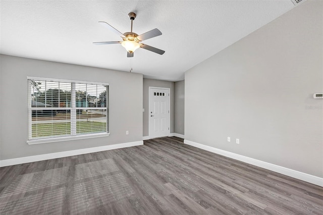 empty room with ceiling fan, wood-type flooring, and a textured ceiling