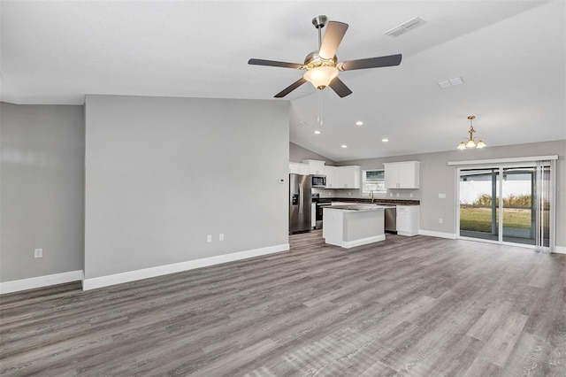 unfurnished living room featuring lofted ceiling, light wood-type flooring, a wealth of natural light, and ceiling fan with notable chandelier