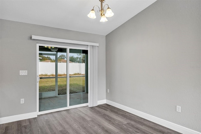 empty room featuring dark hardwood / wood-style flooring and a notable chandelier