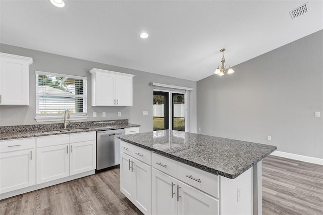 kitchen featuring dishwasher, sink, white cabinetry, and a kitchen island