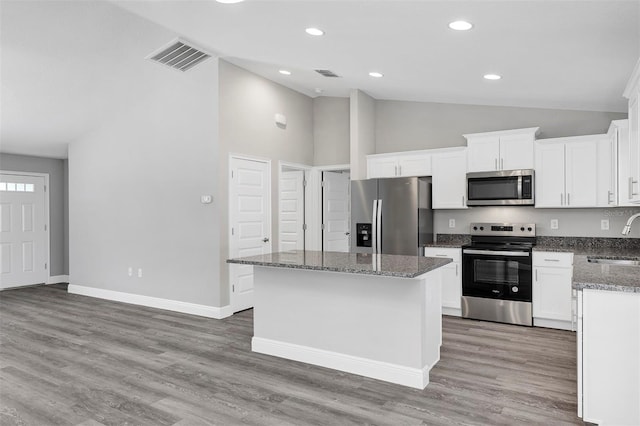 kitchen featuring stainless steel appliances, dark stone countertops, a kitchen island, white cabinets, and sink