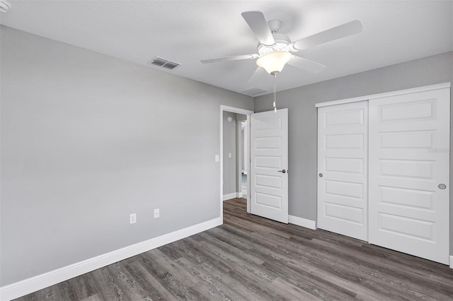 unfurnished bedroom with dark wood-type flooring, ceiling fan, and a closet