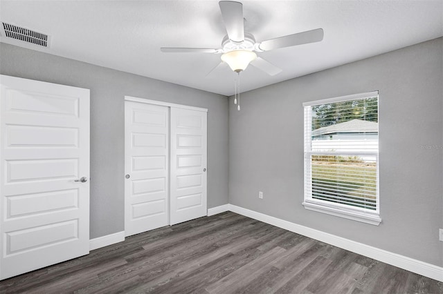 unfurnished bedroom featuring ceiling fan, dark wood-type flooring, and a closet