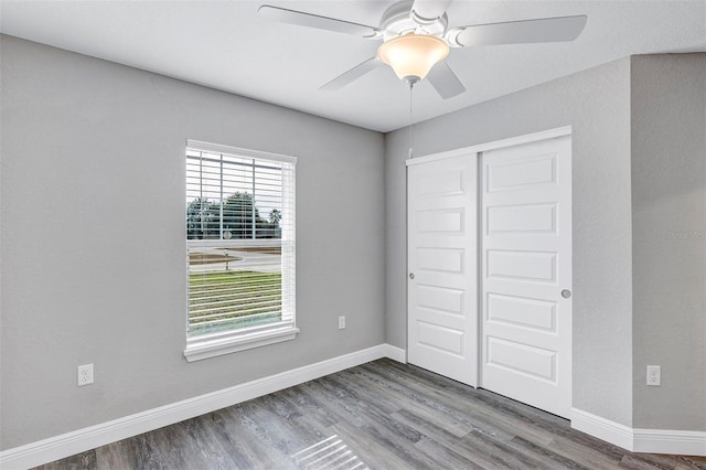 unfurnished bedroom with ceiling fan, wood-type flooring, and a closet