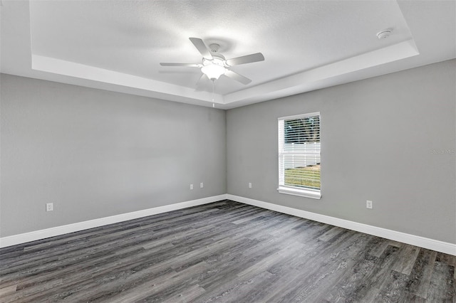 spare room featuring ceiling fan, dark wood-type flooring, and a tray ceiling