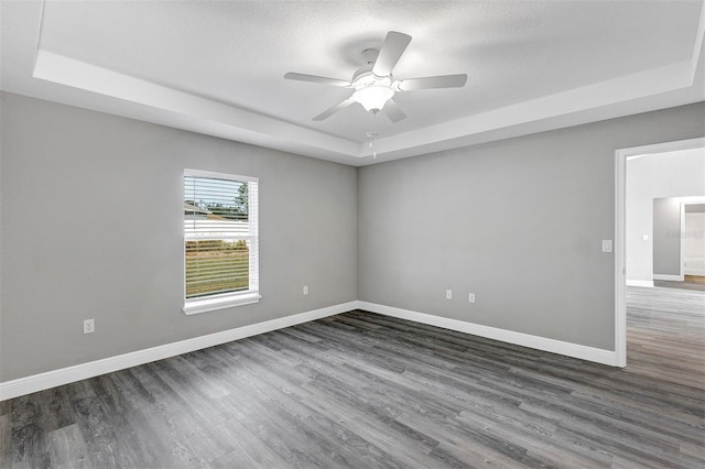 spare room with ceiling fan, a textured ceiling, dark hardwood / wood-style flooring, and a raised ceiling