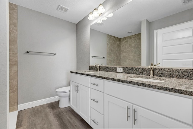 bathroom featuring hardwood / wood-style floors, toilet, vanity, and a textured ceiling