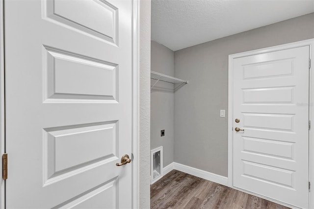 laundry room with a textured ceiling, wood-type flooring, and electric dryer hookup