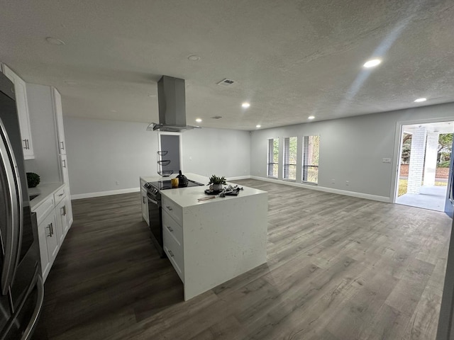 kitchen with island exhaust hood, stainless steel refrigerator, black / electric stove, white cabinets, and a center island