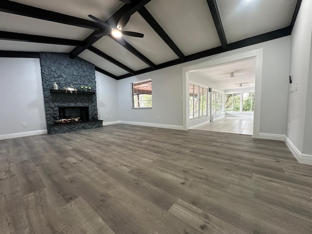 unfurnished living room with ceiling fan, lofted ceiling with beams, a fireplace, and hardwood / wood-style floors