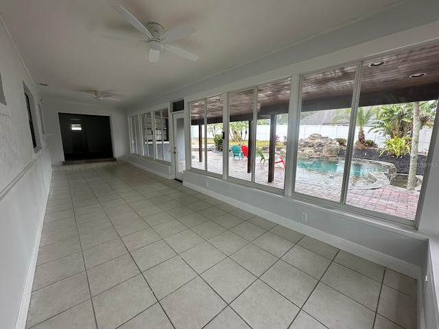 unfurnished sunroom featuring ceiling fan and a wealth of natural light