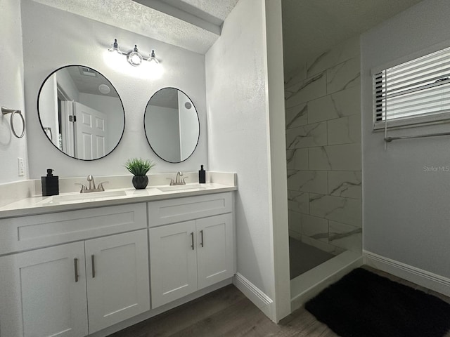 bathroom with vanity, tiled shower, a textured ceiling, and hardwood / wood-style floors