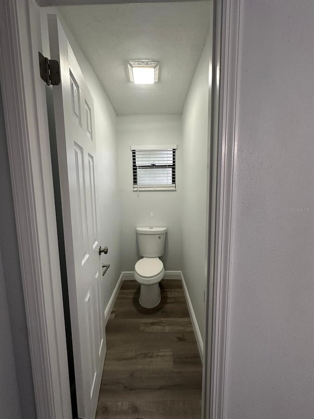 bathroom featuring wood-type flooring, toilet, and a textured ceiling